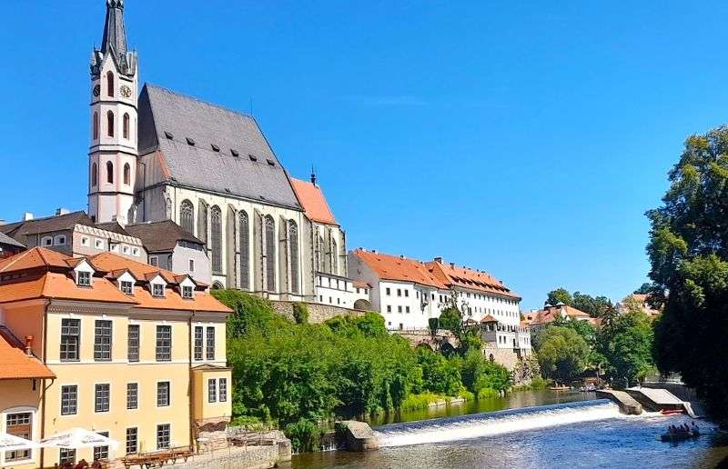 The historic stone Gothic tower of the Church of St. Vitus rising above the old town buildings in Cesky Krumlov
