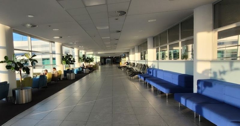 Long blue upholstered benches without armrests in the Terminal 1 air-side relaxation zone at Prague Airport