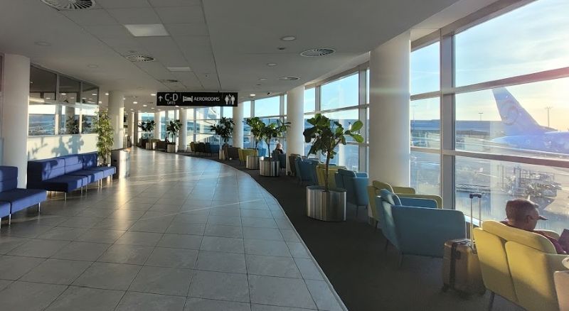 Air-side relaxation seating in Terminal 1 at Prague Airport, with signs for Gates C and D and AeroRooms