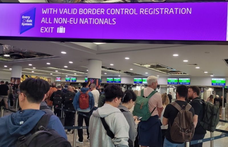 Passengers queuing in front of staffed passport-control counters at Prague Airport Terminal 1.