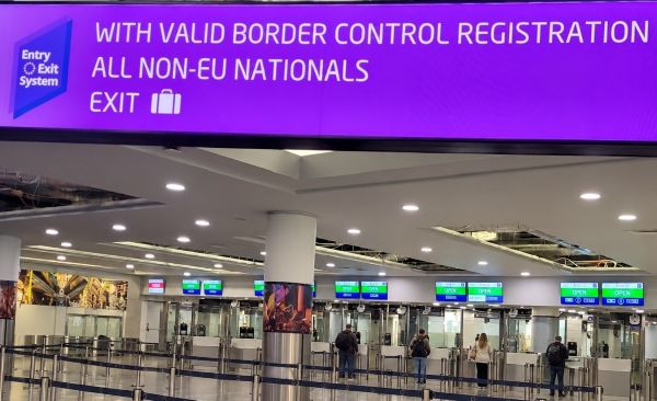 Passport-control counters beneath an EES sign at Prague Airport Terminal 1, with a few passengers being checked.