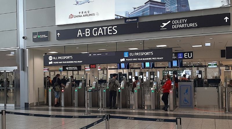 Boarding-pass entrance gates beneath signs for A–B departure gates and passport lanes at Prague Airport.